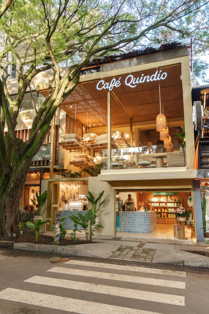 Fachada de Café Quindío rodeada de árboles y luz cálida